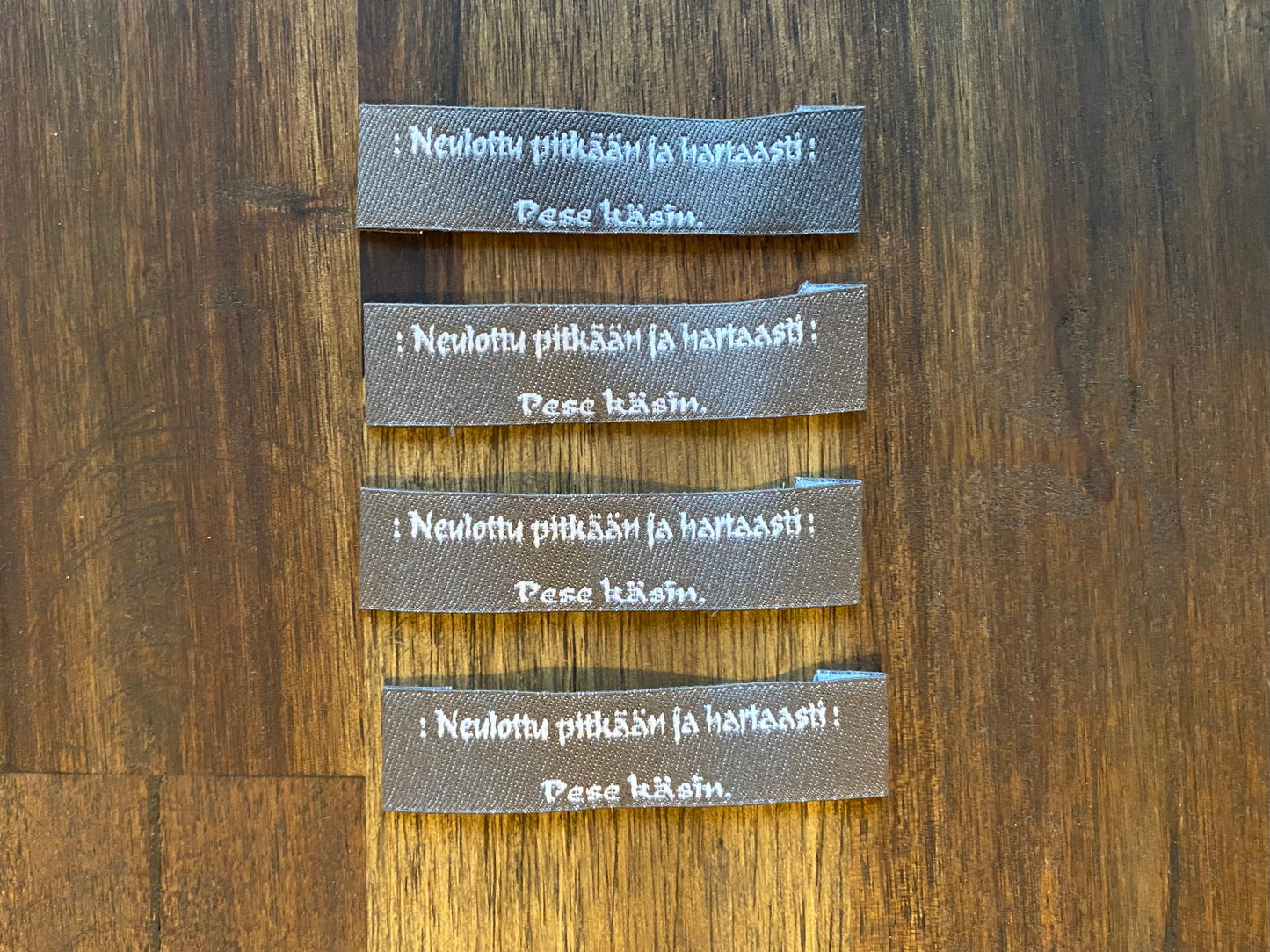 "Neulottu pitkään ja hartaasti. Pese käsin." - Clothing Labels for Knitted Garments - 15 mm height, 60 mm length. 4 pcs. Black, grey, white..