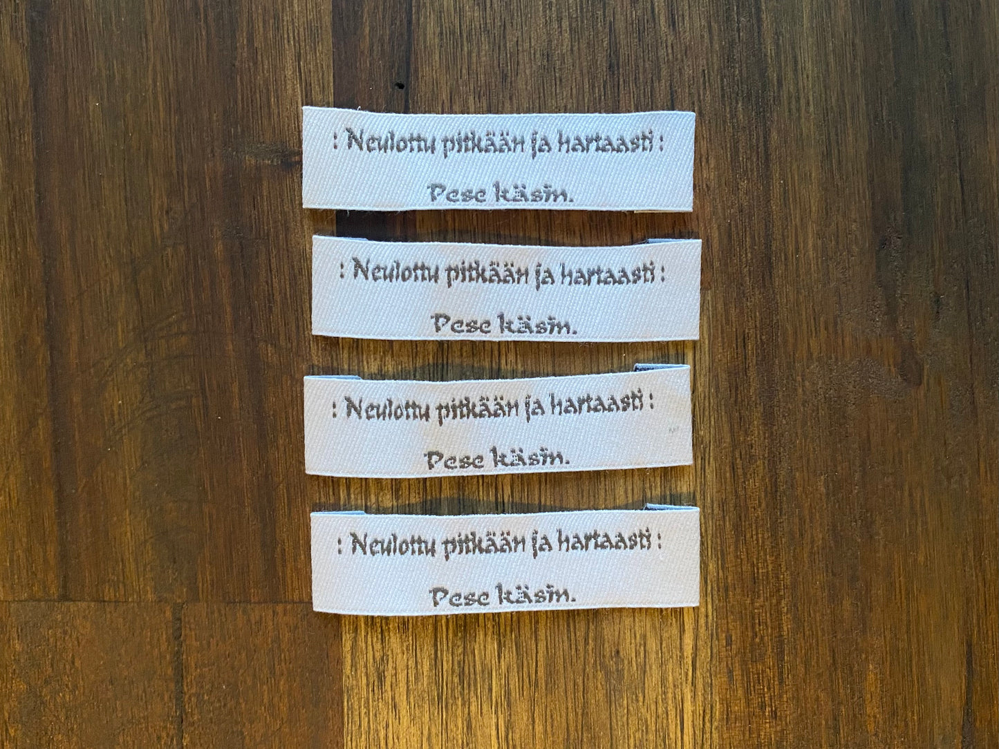 "Neulottu pitkään ja hartaasti. Pese käsin." - Clothing Labels for Knitted Garments - 15 mm height, 60 mm length. 4 pcs. Black, grey, white..